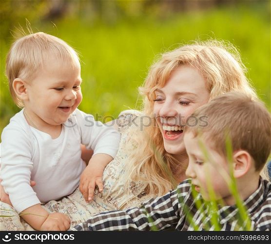 Portrait of a happy mother hugging her sons on the grass. Happy family