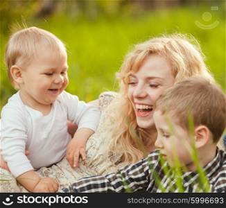 Portrait of a happy mother hugging her sons on the grass. Happy family