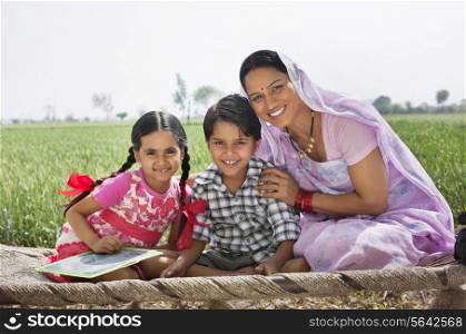 Portrait of a happy mother sitting with her children on cot