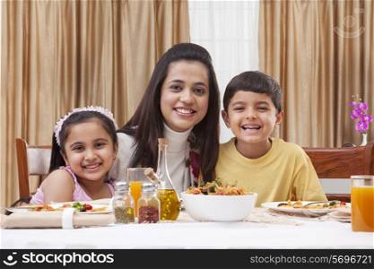 Portrait of a happy mother with her children having pizza at restaurant