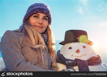 Portrait of a happy nice female outdoors making a snowman, traditional winter play time, happy wintertime vacation