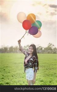 Portrait of a happy pretty woman with balloons in green field. happy pretty woman with balloons