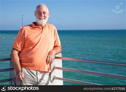 Portrait of a happy senior fisherman with his rod and reel.