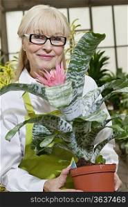 Portrait of a happy senior woman holding pot plant