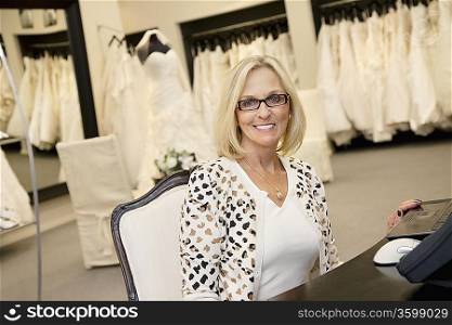 Portrait of a happy senior woman wearing eyeglasses sitting in bridal store