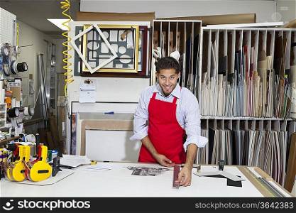 Portrait of a happy skilled worker measuring with meter stick in workshop