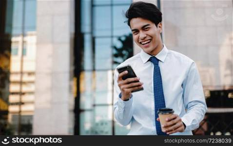 Portrait of a Happy Smiling Asian Businessman Using Mobile Phone in the Urban City. Lifestyle of Modern People. Looking at Camera. Modern Building as background