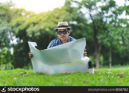 portrait of a happy smiling traveler senior man sit in Forrest, opening a map