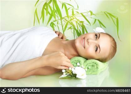 Portrait of a happy smiling woman lying down on a massage table at luxury spa salon, young female enjoying beauty treatment and pampering