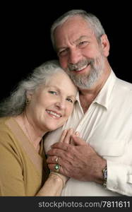 Portrait of a happy, successful middle aged couple over a black background.