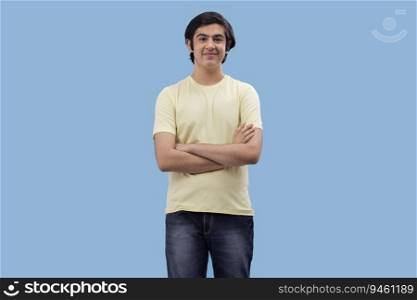 Portrait of a happy teenage boy standing against blue background