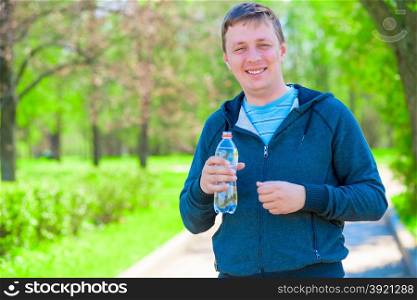 portrait of a happy trainer with a bottle of water during a break between workouts