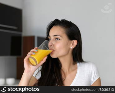 Portrait of a happy woman drinking juice in her kitchen