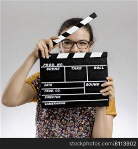 Portrait of a happy woman playing with a clapboard