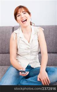 Portrait of a happy woman sitting on sofa and holding a cellphone
