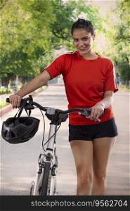 PORTRAIT OF A HAPPY WOMAN STANDING IN FRONT OF CAMERA WITH BICYCLE