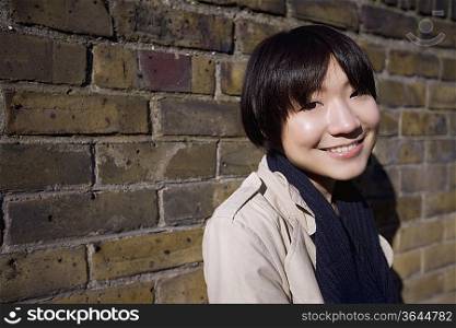 Portrait of a happy young Asian woman against wall