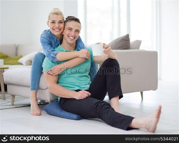Portrait of a happy young beautiful couple hugging and drinking coffee in their new home