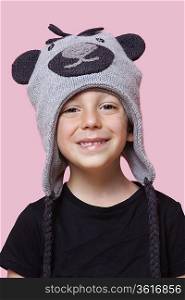 Portrait of a happy young boy wearing monkey cap over pink background