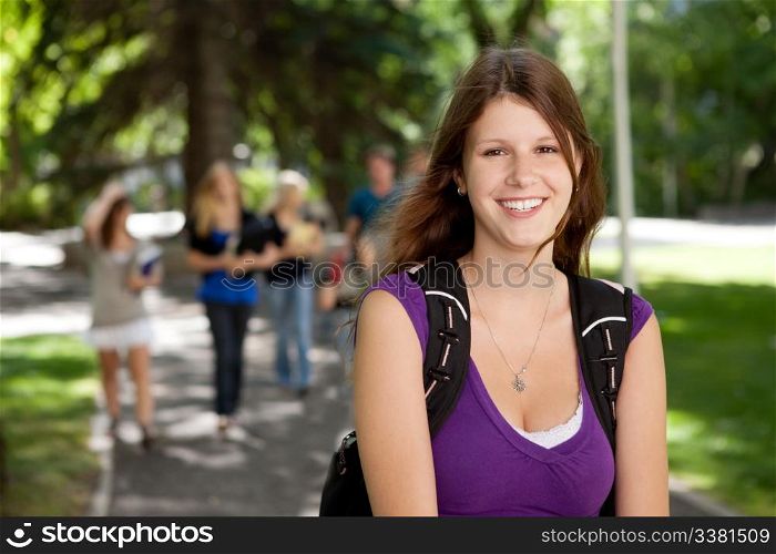 Portrait of a happy young college girl with friends in background