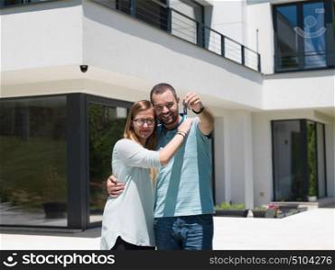 Portrait of a happy young couple hugging in front of their new luxury home villa