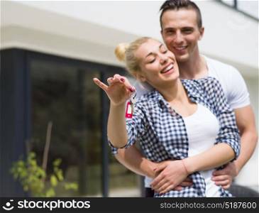 Portrait of a happy young couple hugging in front of their new luxury home villa