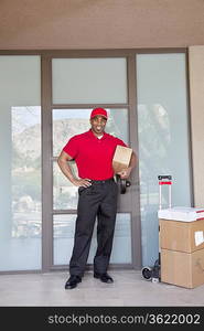 Portrait of a happy young delivery man standing with packages