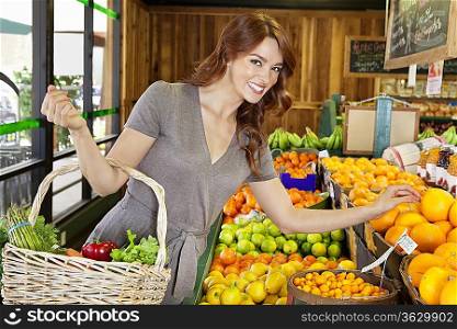 Portrait of a happy young female shopping for fruits in market