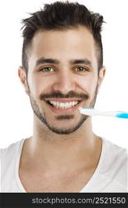 Portrait of a happy young man brushing the teeth
