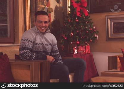 Portrait of a happy young man celebrating winter holidays at home beautifully decorated for Christmas