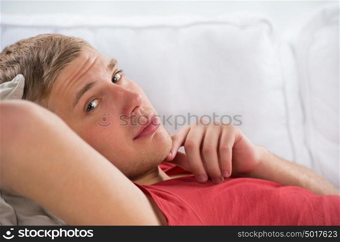 Portrait of a happy young man laying on sofa in thought