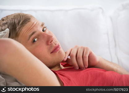 Portrait of a happy young man laying on sofa in thought