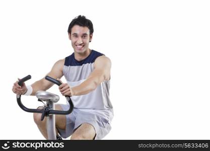 Portrait of a happy young man on exercise bike over white background