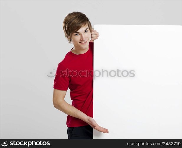 Portrait of a happy young man showing something on a blank white card