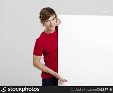 Portrait of a happy young man showing something on a blank white card