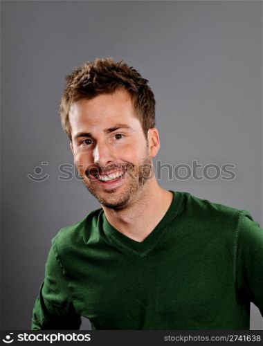 Portrait of a happy young man. Studio shot on a gray background.