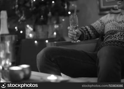 Portrait of a happy young man with a glass of champagne celebrating winter holidays at home beautifully decorated for Christmas