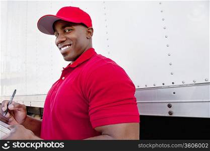 Portrait of a happy young man with delivery truck in background