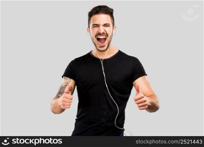 Portrait of a happy young man with thumbs up and listen music
