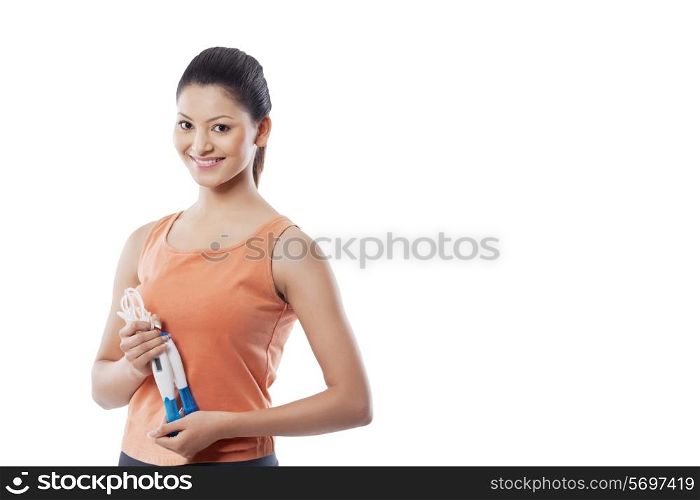 Portrait of a happy young woman holding jump rope over white background