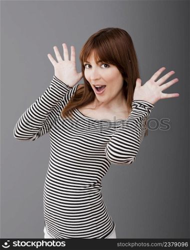 Portrait of a happy young woman with a funny expression over a gray background
