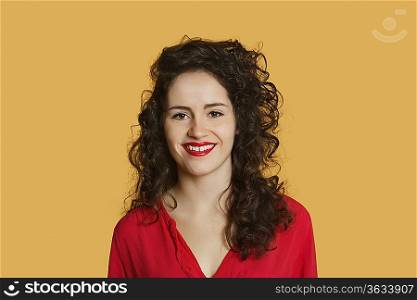 Portrait of a happy young woman with curly hair over colored background