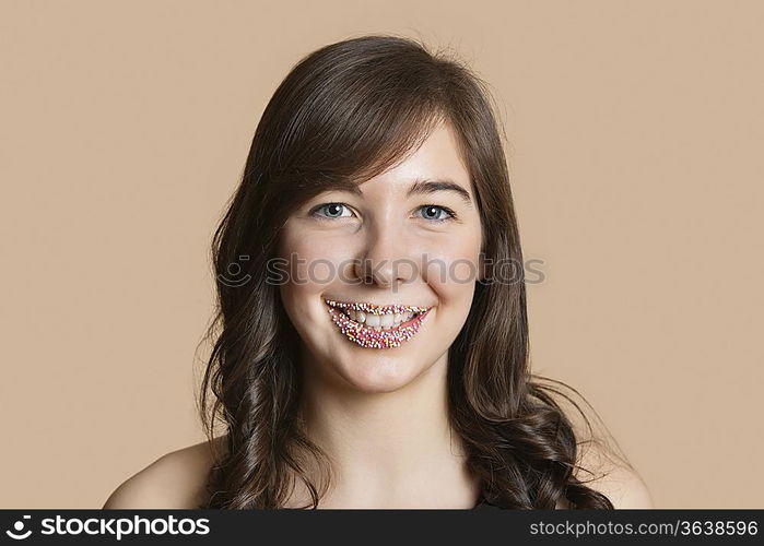 Portrait of a happy young woman with sprinkled lips over colored background