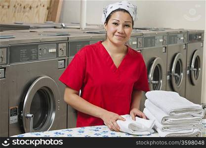 Portrait of a Hispanic female employee with towel in Laundromat