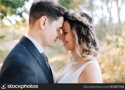 Portrait of a just married couple bringing their foreheads together in the woods