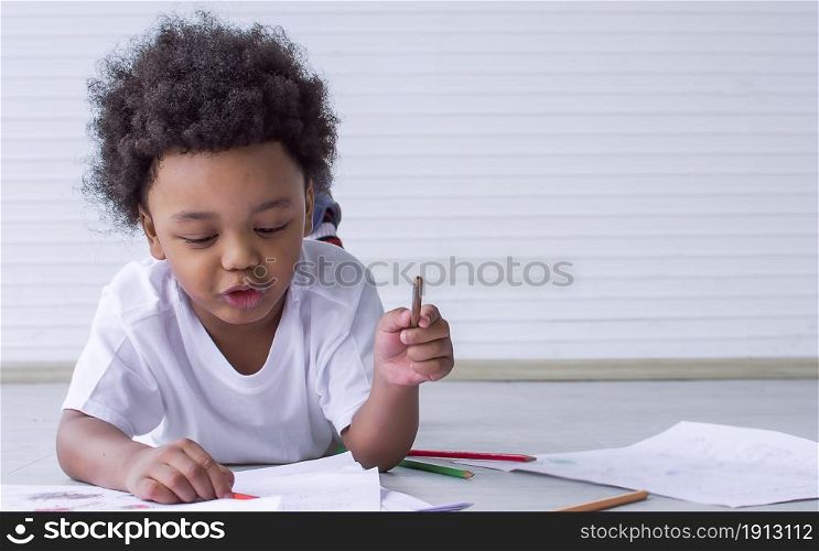 Portrait of a little african boy is drawing and painting while staying at home with copy space. Education Concept.
