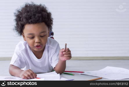 Portrait of a little african boy is drawing and painting while staying at home with copy space. Education Concept.