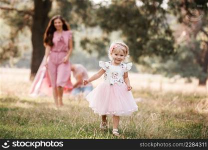Portrait of a little beautiful girl on nature on summer day vacation. child in red dress is playing in the green grass at the sunset time. The concept of family holiday and time together.. Portrait of a little beautiful girl on nature on summer day vacation. child in red dress is playing in the green grass at the sunset time. The concept of family holiday and time together