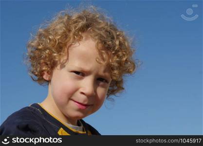 Portrait of a little boy with blond and curly hair