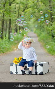 Portrait of a little boy with s suitcase in forest